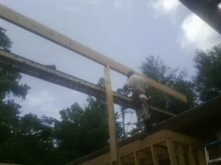 Carpenter setting a ridge beam over a new addition frame — Ice Dam Removal by Roofing Brothers in Maynard