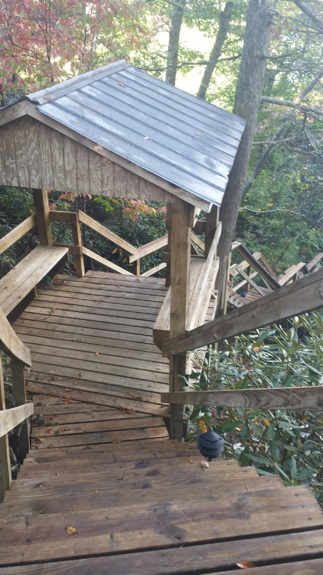 Metal roofed shelter over wooden steps on a wooded walkway — Skylight Repair & Installation work by our crew in Maynard